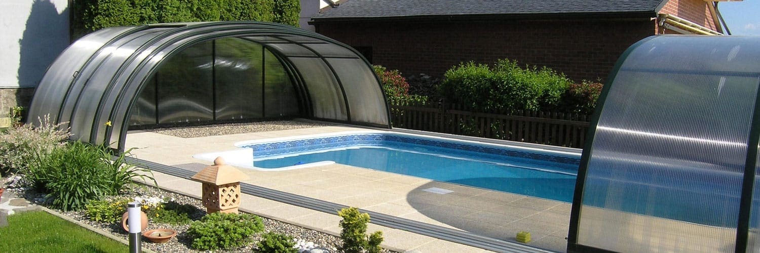 Piscina interrata con copertura in vetro e all'aperto, zona wellness e giardino curato.