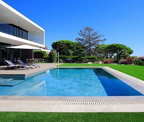 Piscina interrata con bordo a sfioro in un giardino ben curato, ideale per relax e wellness.