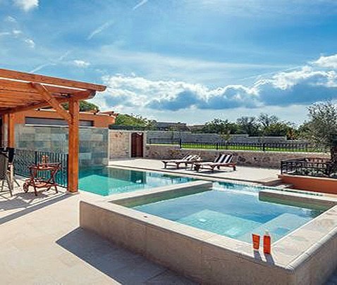 Piscina interrata con spa e area relax all'aperto sotto un cielo sereno.